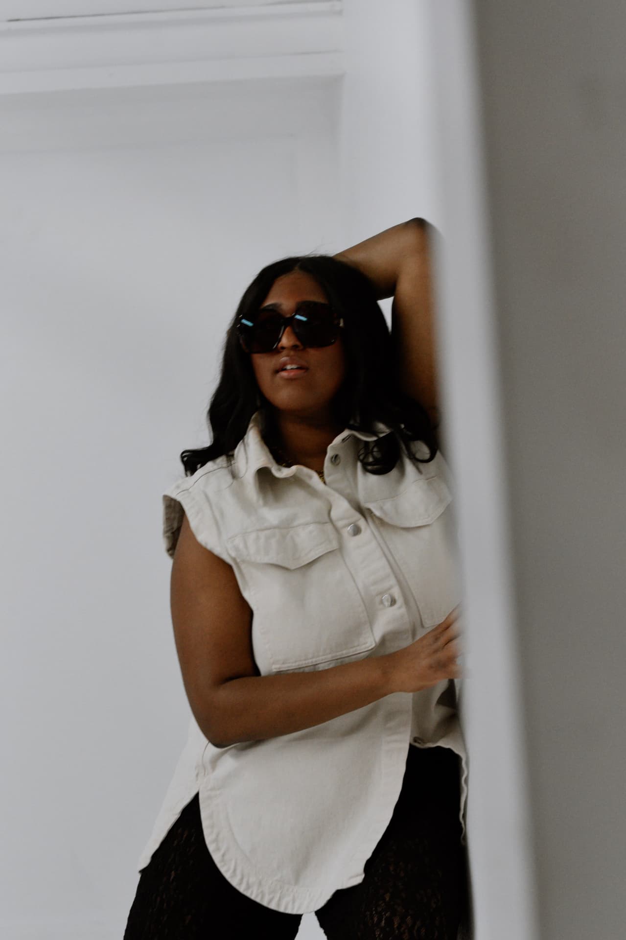 Artisha Walker in sunglasses leaning against a studio wall